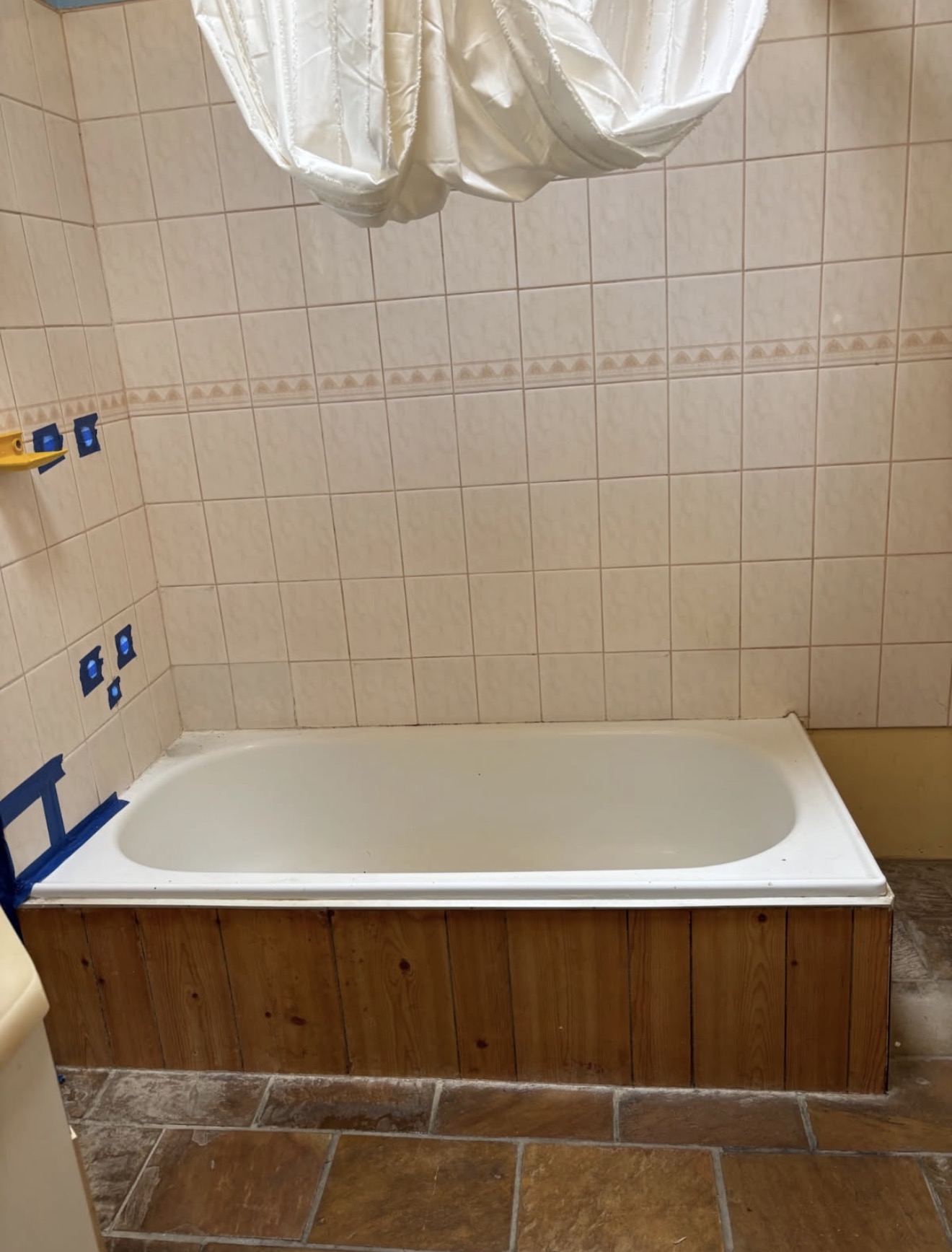 Bathroom with an old bathtub and dated wall tiles before renovation